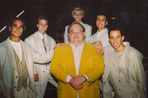 Boy band standing with old man in the center in Dirty Pop: The Boy Band Scam